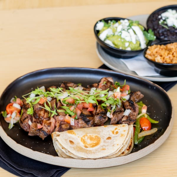 El Barrio's grilled steak fajitas with tortillas, guacamole, black beans, and rice.