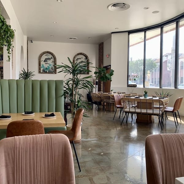 El Barrio Cantina's dining room with green booths, light wood tables, and large windows.