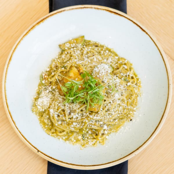 El Barrio's spaghetti with green sauce, topped with cheese, chicken, and microgreens.